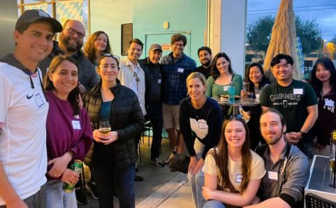 A group of Canyon Young Dems standing and sitting together on a restaurant patio during a happy hour event.